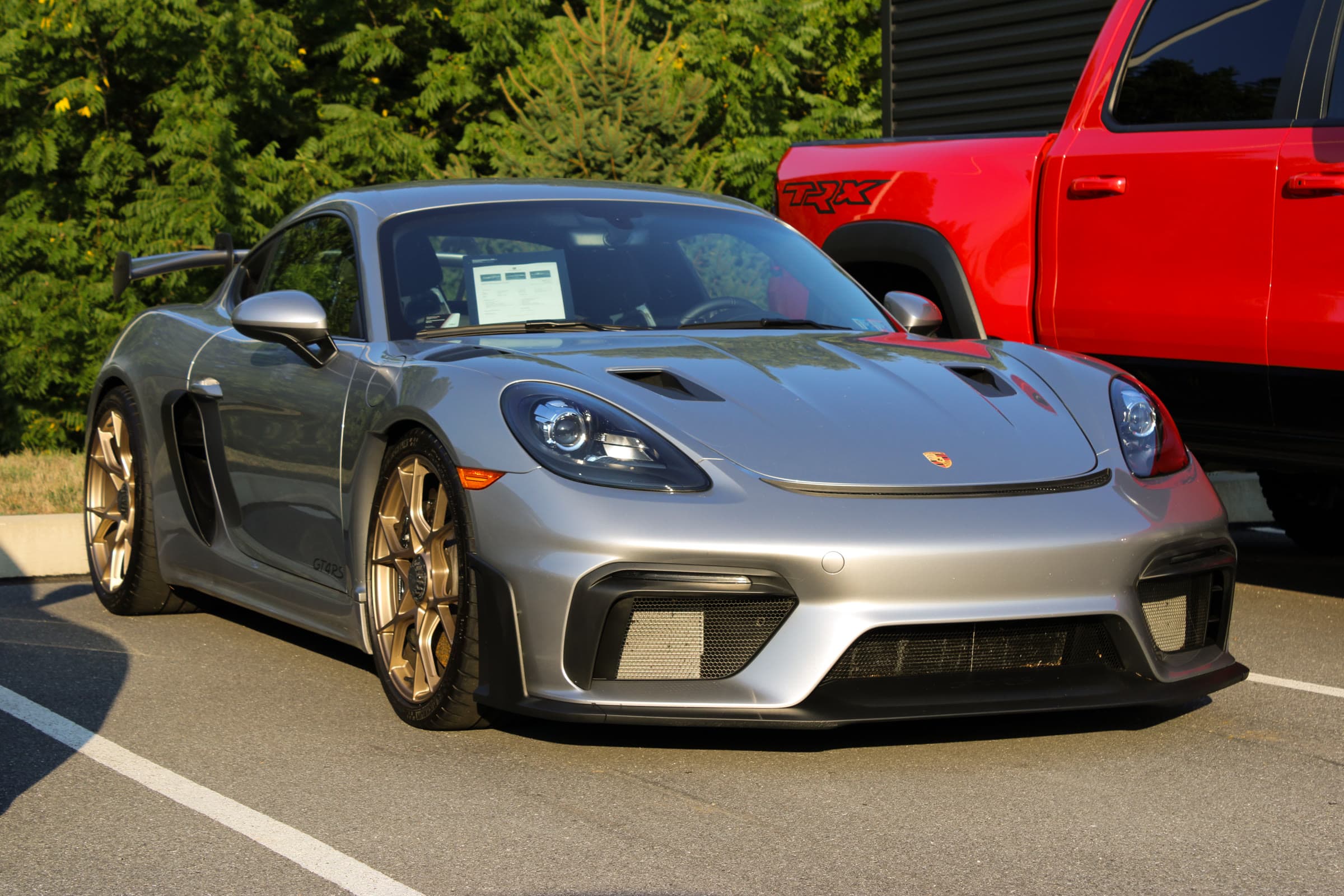 Conrad Captures photograph: silver Porsche 718 Cayman GT4 RS, front three-quarter at golden hour.